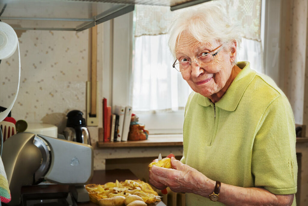 independent living senior mother cutting some vegetables in kitchen